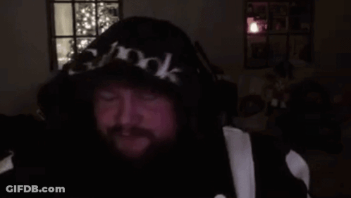 A Man With A Beard Is Wearing A Hoodie And Headphones And Making A Funny Face . GIF