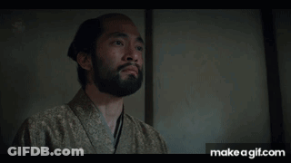 A Man With A Beard Is Wearing A Kimono And Looking At Something GIF