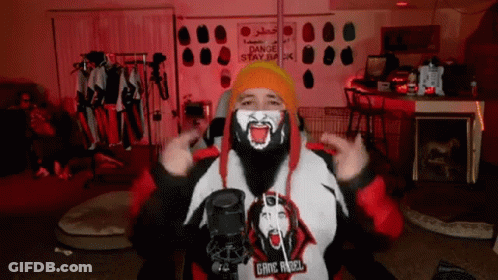 A Man With A Beard Is Wearing A Mask And A Hoodie That Says Gang Angel GIF