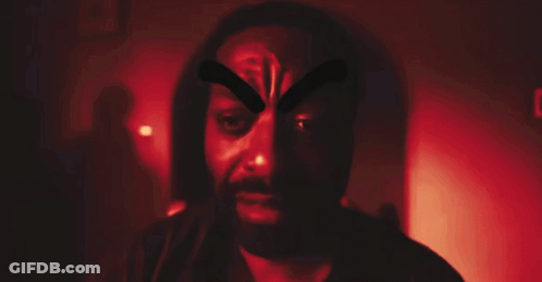 A Man With A Beard Is Wearing A Mask With A Cross On His Face GIF