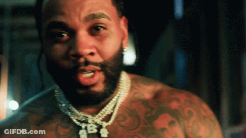 A Man With A Beard Is Wearing A Necklace That Says Tba On It GIF