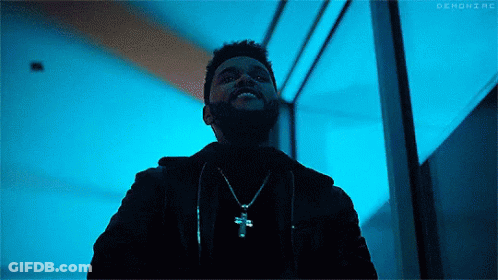 A Man With A Beard Is Wearing A Necklace With A Cross On It And Smiling . GIF