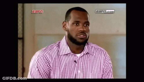 A Man With A Beard Is Wearing A Pink And White Striped Shirt And Talking To A Microphone . GIF