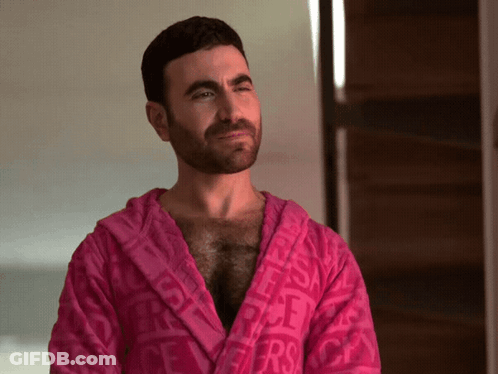 A Man With A Beard Is Wearing A Pink Robe With The Word Versace Printed On It GIF
