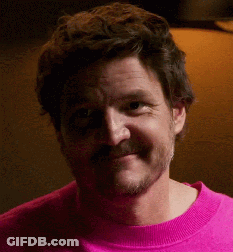 A Man With A Beard Is Wearing A Pink Sweater And Smiling GIF
