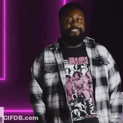 A Man With A Beard Is Wearing A Plaid Shirt And A Black Shirt GIF