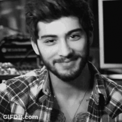 A Man With A Beard Is Wearing A Plaid Shirt And Smiling . GIF