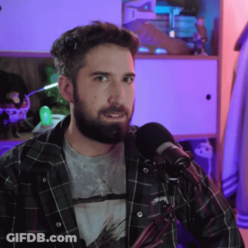 A Man With A Beard Is Wearing A Plaid Shirt With Stussy On It GIF