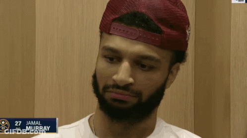 A Man With A Beard Is Wearing A Red Hat And The Name Jamal Murray Is On A Sign GIF