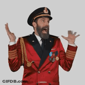 A Man With A Beard Is Wearing A Red Jacket And A Black Hat . GIF