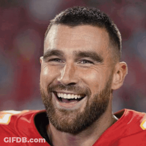 A Man With A Beard Is Wearing A Red Jersey And Smiling . GIF