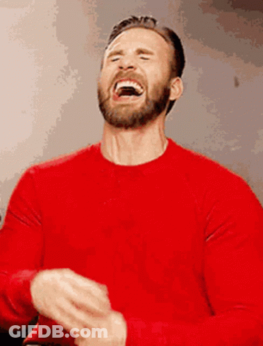 A Man With A Beard Is Wearing A Red Shirt And Laughing . GIF