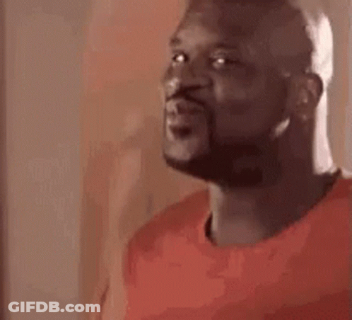 A Man With A Beard Is Wearing A Red Shirt And Looking At The Camera . GIF