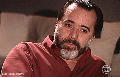 A Man With A Beard Is Wearing A Red Shirt With The Letter O On The Bottom Right GIF