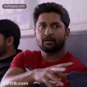 A Man With A Beard Is Wearing A Red T-Shirt And Pointing His Finger . GIF