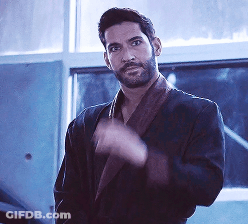 A Man With A Beard Is Wearing A Robe And Waving His Hand In Front Of A Window . GIF