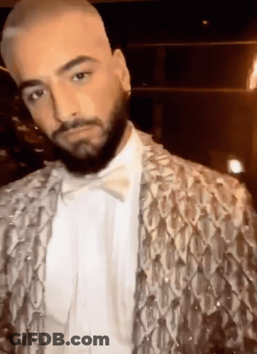 A Man With A Beard Is Wearing A Sequined Jacket And A Bow Tie GIF