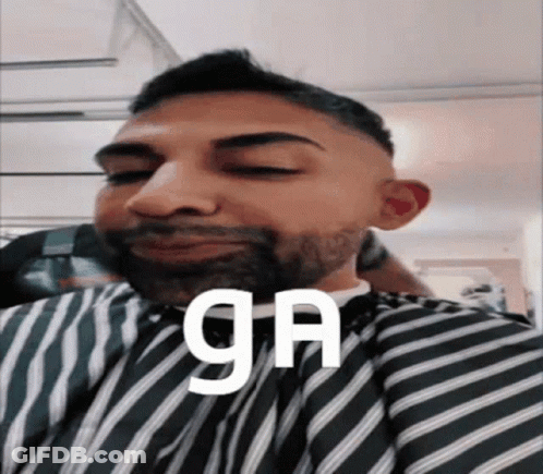 A Man With A Beard Is Wearing A Striped Cape And The Word Ga Is On His Face GIF