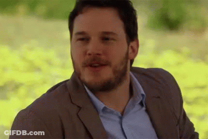 A Man With A Beard Is Wearing A Suit And A Blue Shirt And Is Smiling . GIF