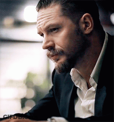 A Man With A Beard Is Wearing A Suit And A White Shirt . GIF