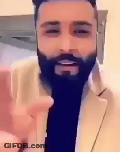 A Man With A Beard Is Wearing A Suit And Giving A Peace Sign GIF