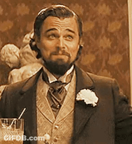 A Man With A Beard Is Wearing A Suit And Tie And Holding A Glass Of Water . GIF