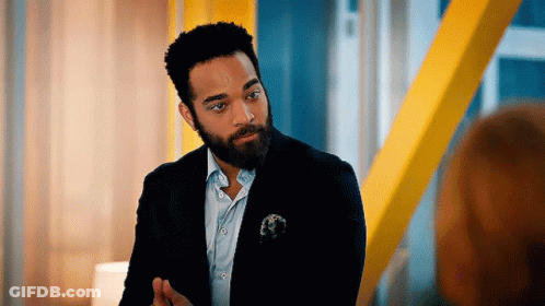 A Man With A Beard Is Wearing A Suit And Tie And Talking To Another Man . GIF