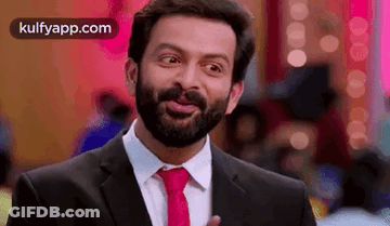 A Man With A Beard Is Wearing A Suit And Tie . GIF