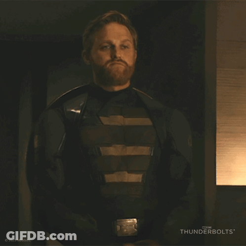 A Man With A Beard Is Wearing A Thunderbolts Costume And Holding A Shield . GIF