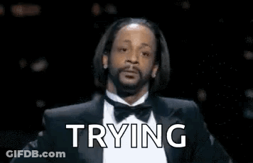 A Man With A Beard Is Wearing A Tuxedo And Bow Tie And Says `` Trying '' . GIF