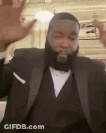 A Man With A Beard Is Wearing A Tuxedo And Dancing . GIF