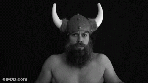 A Man With A Beard Is Wearing A Viking Helmet With Horns GIF