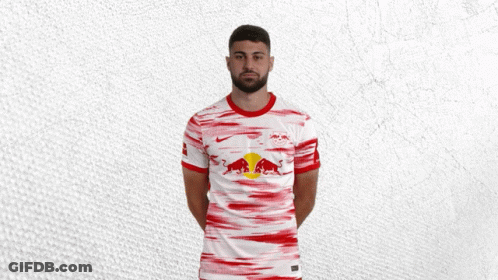 A Man With A Beard Is Wearing A White And Red Shirt With Red Bulls On It GIF