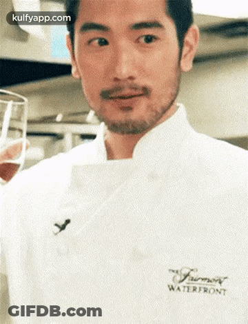 A Man With A Beard Is Wearing A White Chef 'S Coat And Holding A Glass . GIF