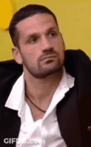 A Man With A Beard Is Wearing A White Shirt And A Black Jacket GIF