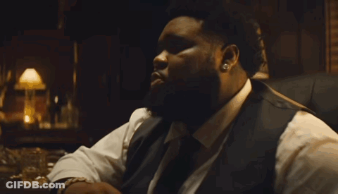 A Man With A Beard Is Wearing A White Shirt And A Black Vest . GIF