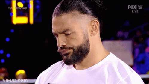 A Man With A Beard Is Wearing A White Shirt And A Bun . GIF