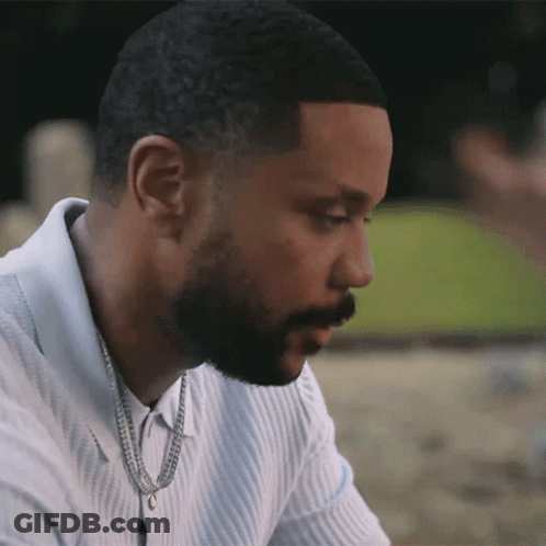 A Man With A Beard Is Wearing A White Shirt And A Gold Chain Around His Neck GIF