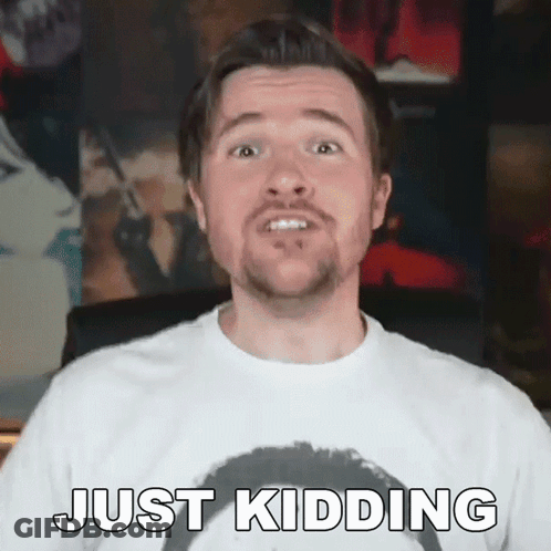 A Man With A Beard Is Wearing A White Shirt And Making A Funny Face While Saying Just Kidding . GIF
