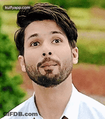 A Man With A Beard Is Wearing A White Shirt And Tie And Looking Up . GIF