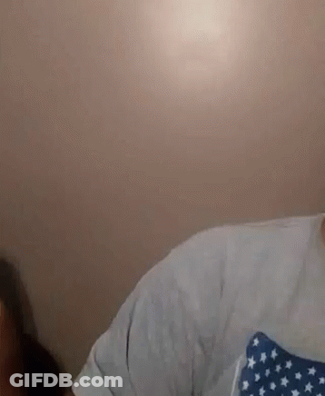 A Man With A Beard Is Wearing A White Shirt With A Blue And White American Flag On It . GIF