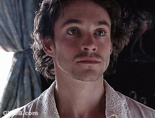 A Man With A Beard Is Wearing A White Shirt With A Lace Collar GIF
