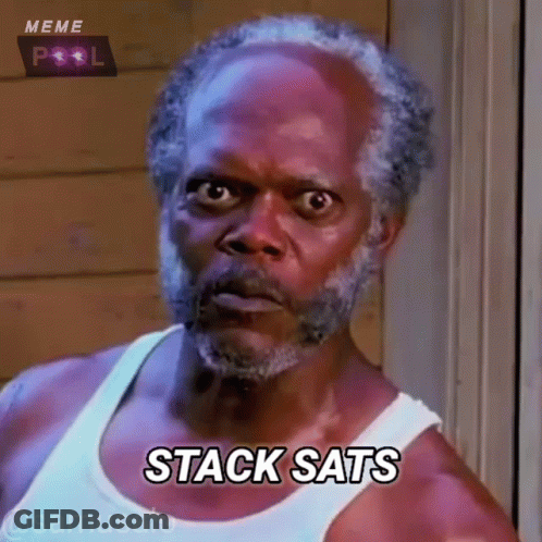 A Man With A Beard Is Wearing A White Tank Top And Saying Stack Sats GIF