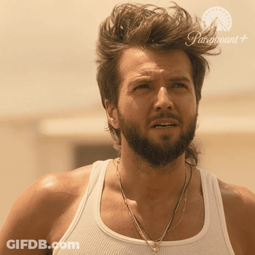 A Man With A Beard Is Wearing A White Tank Top With Paramount Written On The Bottom GIF
