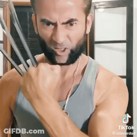 A Man With A Beard Is Wearing A Wolverine Costume And Holding His Claws Out . GIF