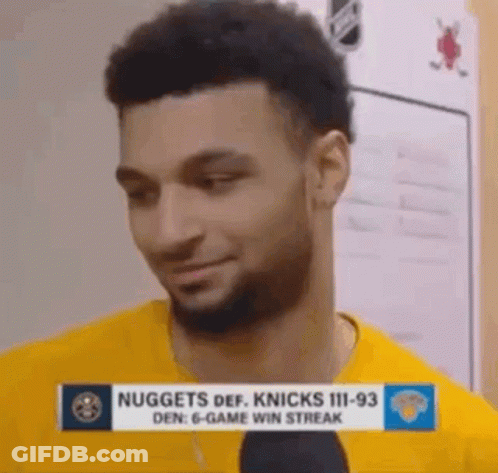 A Man With A Beard Is Wearing A Yellow Shirt And Talking Into A Microphone In A Locker Room . GIF