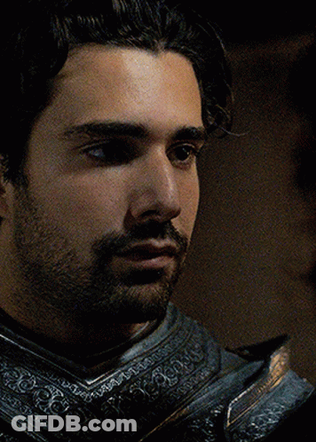 A Man With A Beard Is Wearing Armor And Looking At Something GIF