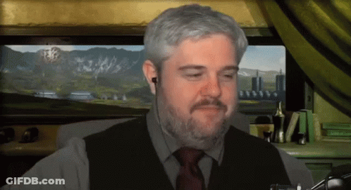 A Man With A Beard Is Wearing Ear Buds And A Vest And Tie GIF