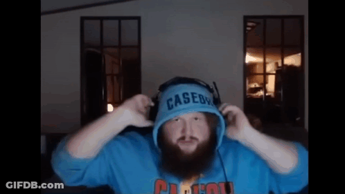 A Man With A Beard Is Wearing Headphones And A Blue Casedy Hoodie . GIF