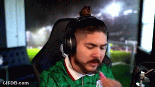 A Man With A Beard Is Wearing Headphones And A Green Shirt . GIF
